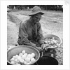 American soldier peeling onions while wearing a gas mask by Alan Villiers