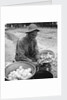 American soldier peeling onions while wearing a gas mask by Alan Villiers