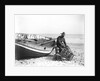 A fisherman in sou'wester mending lobster/crab creels on the beach alongside a beached Sheringham crab boat by Smiths Suitall Ltd.