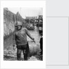 A Folkestone fisherman in smock and sou'wester carrying a tub for fish on the slipway by unknown