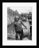 A Folkestone fisherman in smock and sou'wester carrying a tub for fish on the slipway by unknown