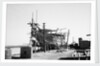 The teak planking of the hull of a large book hull nears completion on the foreshore by Alan Villiers