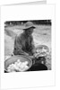 American soldier peeling onions while wearing a gas mask by Alan Villiers