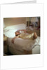 Modern convenience aboard a cruise liner: a female passenger reclines in bed whilst making a phone call; the ship and the conversation's content are unspecified by Marine Photo Service