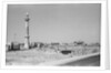 Minaret, stacked building stone and new buildings, Manama by Alan Villiers