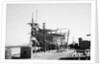 The teak planking of the hull of a large book hull nears completion on the foreshore by Alan Villiers