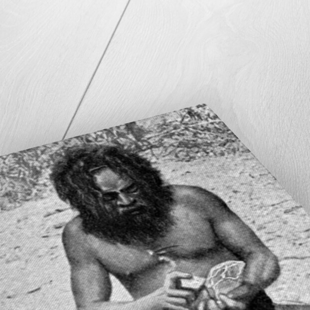 A man from the Warramunga tribe making a stone axe head, Australia by Spencer and Gillen