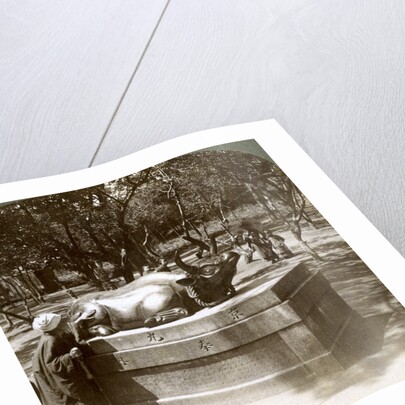 Devout woman stroking a bronze bull to cure rheumatism, Kitano Tenjin temple, Kyoto, Japan by Underwood & Underwood