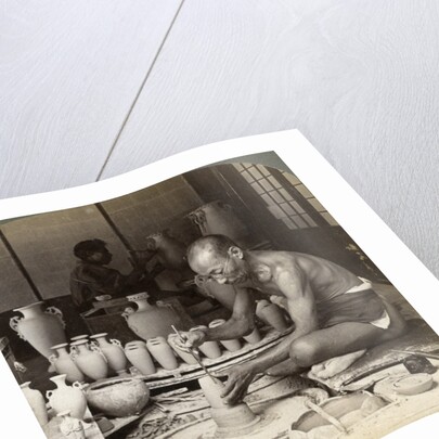 A potter and his wheel, fashioning a vase of Awata porcelain, Kinkosan works, Kyoto, Japan by Underwood & Underwood