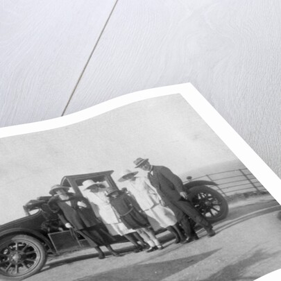 A group of people in front of their car at the seaside by Anonymous