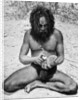 A man from the Warramunga tribe making a stone axe head, Australia by Spencer and Gillen