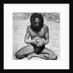 A man from the Warramunga tribe making a stone axe head, Australia by Spencer and Gillen