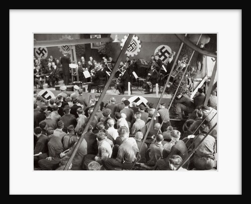 An orchestra plays to some factory workers as they take a break from work by Anonymous