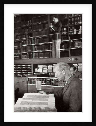 A labourer reads a book in a library by Anonymous
