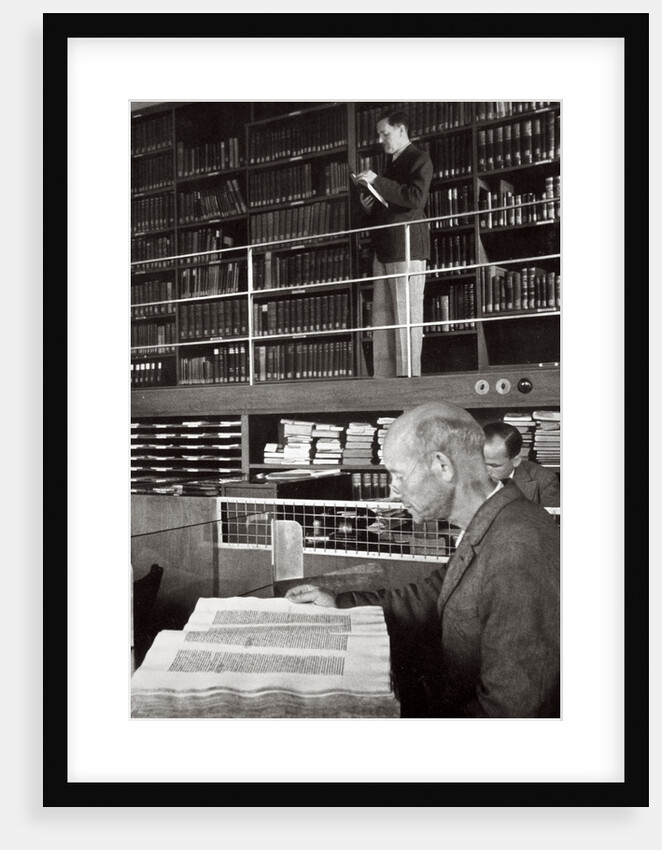 A labourer reads a book in a library by Anonymous