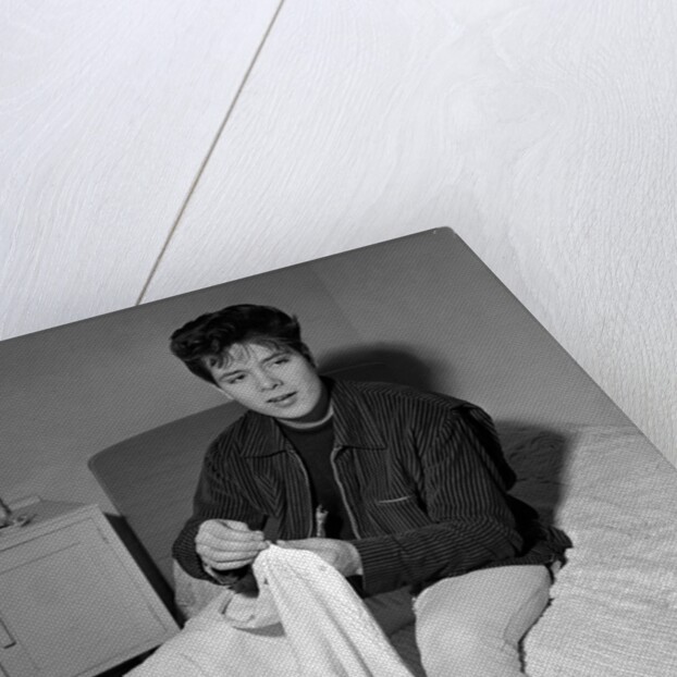 Cliff Richard in his first house sitting on a bed by Harry Hammond