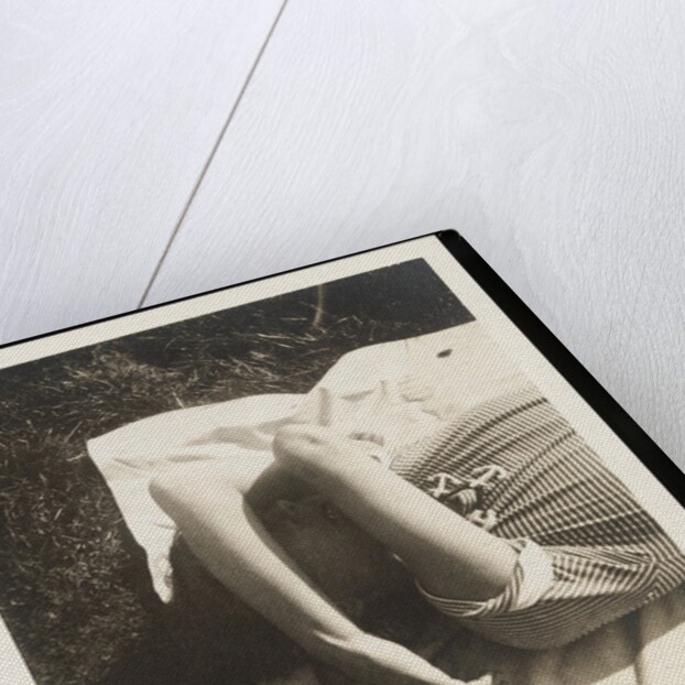 Woman wearing striped t-shirt lying on rug with both arms covering face by Curtis Moffat