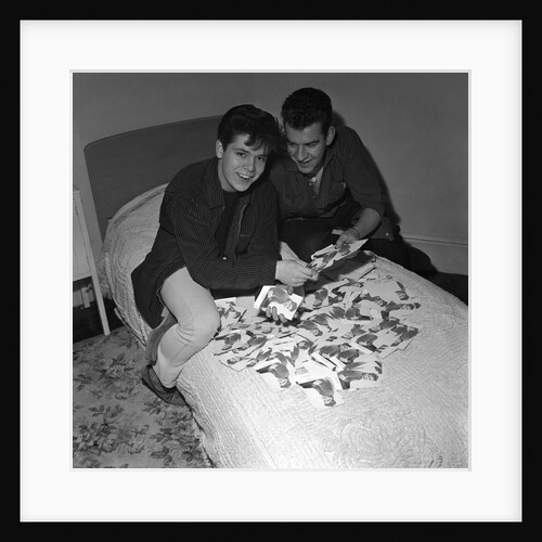 Cliff Richard looking some promotional photographs by Harry Hammond