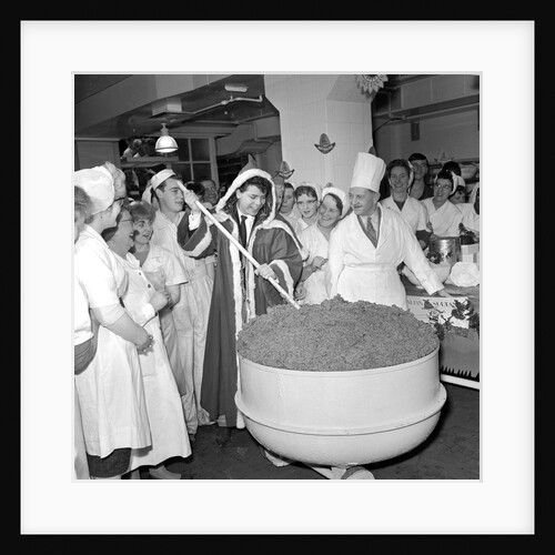 Cliff Richard mixing a giant Christmas pudding at J.Lyons in Cadby Hall, Hammersmith by Harry Hammond
