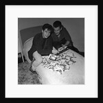 Cliff Richard looking some promotional photographs by Harry Hammond