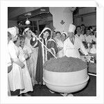 Cliff Richard mixing a giant Christmas pudding at J.Lyons in Cadby Hall, Hammersmith by Harry Hammond